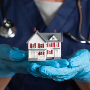 Nurse in gloves holding a small model home