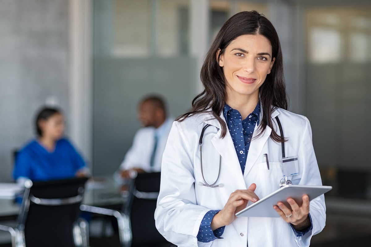 Female physician in lab coat looking at ipad