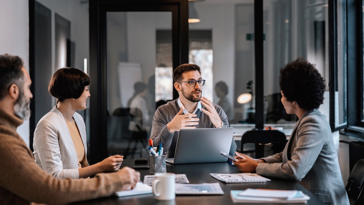 Man talking in from of latptop while meeting with co-workers