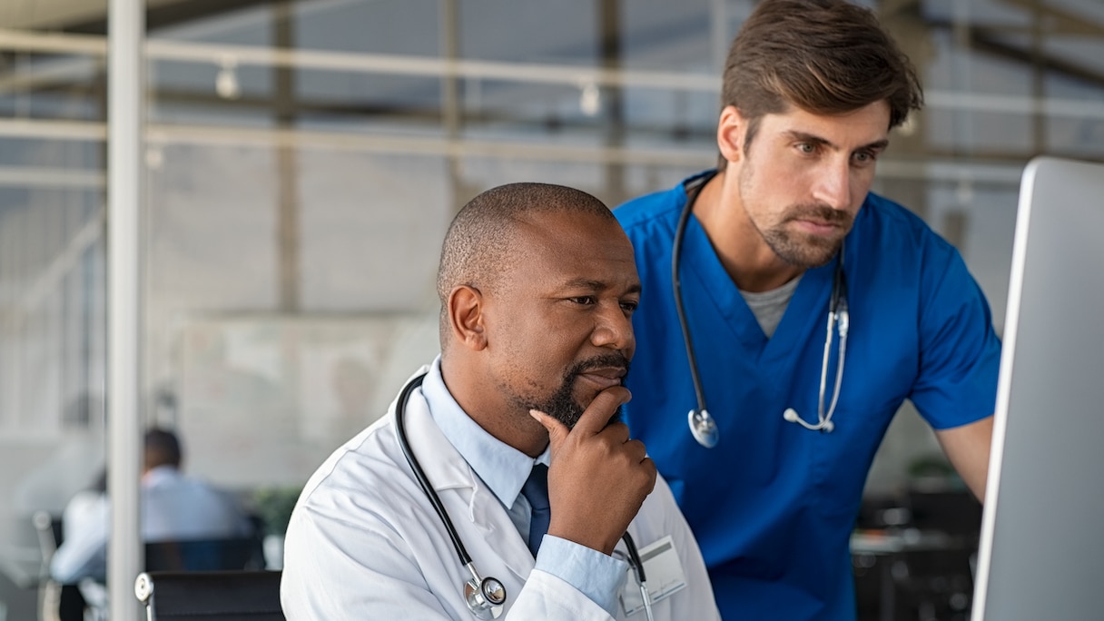 Physician looking at computer with male nurse