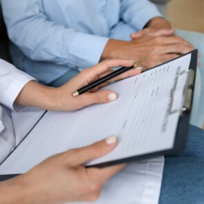 Close up female doctor holding clipboard, filling older patient form, documents, medical history or anamnesis, disease prevention, healthcare, health insurance contract, mature woman checkup